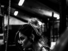 greyscale photo of woman in bralette inside room