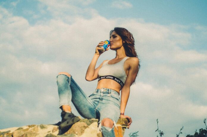 woman sitting on rocky hill drinking soda can during daytime