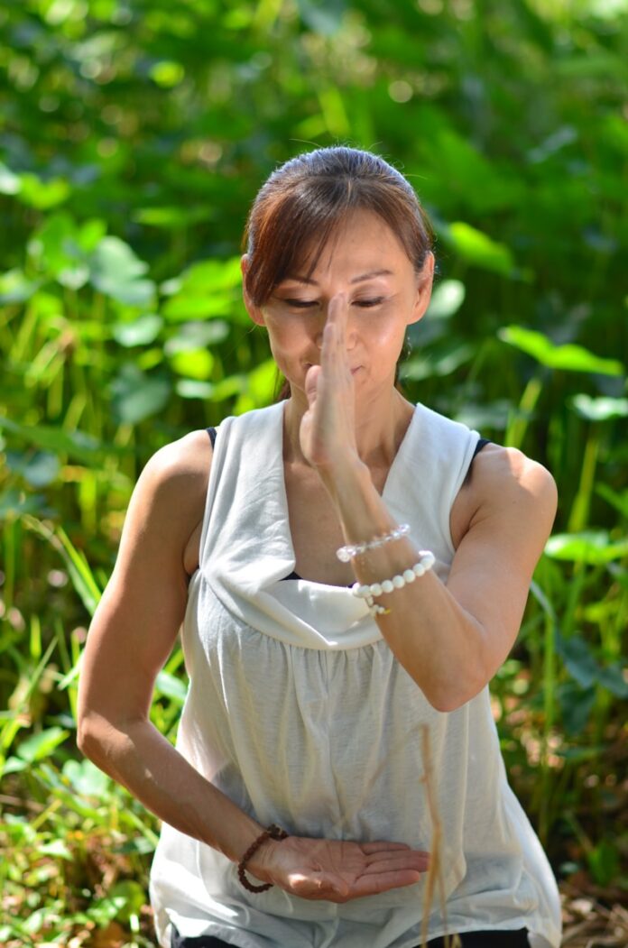 A woman standing in a field of grass blowing her nose