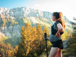 woman in black tank top and black shorts holding black camera standing on brown and green