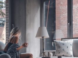 woman sitting on gray sofa chair holding mug