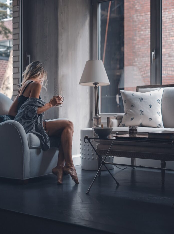 woman sitting on gray sofa chair holding mug